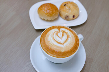 A wooden table with a fragrant cappuccino and baked bread