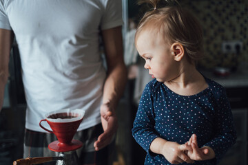 Father teaches his daughter to cook at home in the kitchen. Dad makes coffee at home.