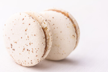 Close up of two white macarons on white background. Salted caramel macaroon