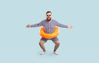 Funny fat man in retro swimsuit and sunglasses poses with swim tube around his waist isolated on...
