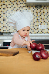 Little girl cooking in the kitchen wearing an apron and a Chef's hat