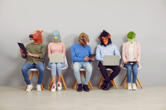 Funny people with animal faces using computers while waiting for business appointment or job interview. Young employees or applicants in silly masks sitting in line and working on laptops and tablets