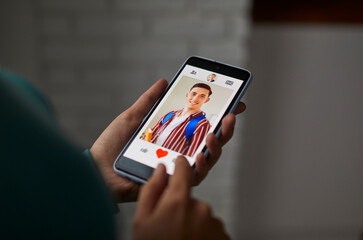 Unrecognizable person giving like to photo on social media. Person swiping and liking profiles on online dating application to find love, partner and boyfriend. Dating app or site on smartphone screen