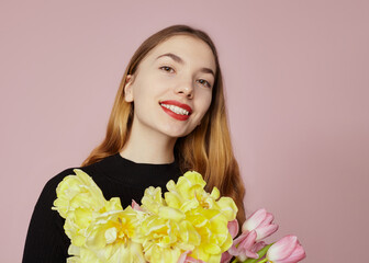 a happy woman with a bouquet of tulips smiles happily looking at the camera