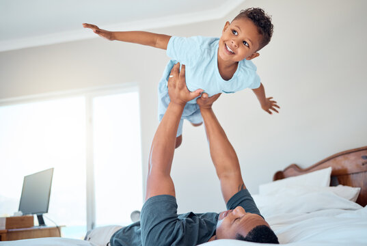 Father lifting kid in air in the bedroom having fun, playing and enjoying morning together. Bonding, love and dad holding young child in bed to pretend to fly for quality time and relax with family