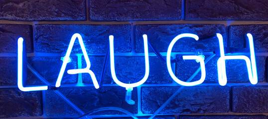 Blue neon sign that says the word LAUGH.