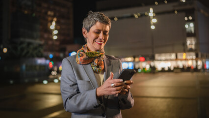 Senior woman use mobile phone send sms text message in city at night