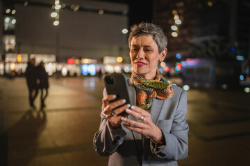 Senior woman use mobile phone send sms text message in city at night