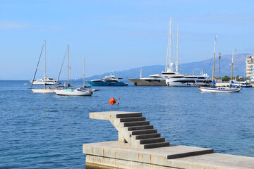Fototapeta premium Beautiful spring city landscape on the port of Saranda. Breathtaking Mediterranean seascape with steps into the sea. Beautiful morning scene of Albania, Europe. Travel concept background.