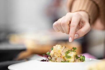 Chef cooks in kitchen restaurant fish, closeup details of preparation of dishes in frying pan and saucepan