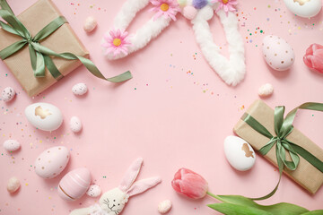 cute easter composition. painted eggs, gifts, flowers, confetti and a toy bunny on a pastel pink background. top view. copy space. flat lay. place for text