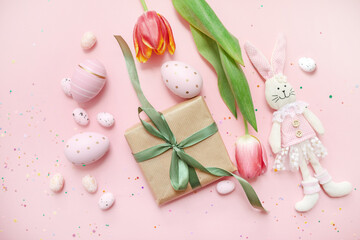 cute easter composition. painted eggs, gifts, flowers, confetti and a toy bunny on a pastel pink background. top view. copy space. flat lay. place for text