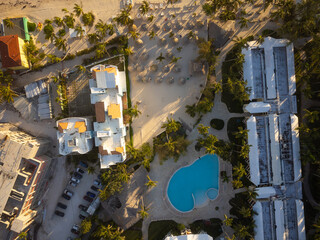 Shooting from a drone. Resort place. On the sandy seashore there is a lot of tropical greenery, the roofs of hotels, small houses, cars. Tourism, construction, recreation, infrastructure.