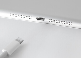 View of Apple Lightning cable and gadget on a white table with empty space, close-up.
