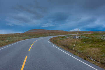 Empty road through the tundra of central Norway with cloudy and  moody sky