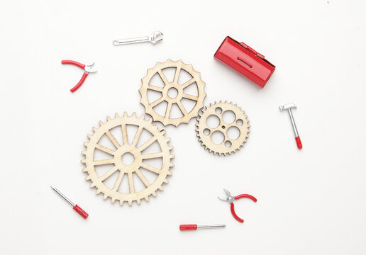 Flatlay picture of wooden gear with tools miniature on white background. Fix the mechanical part concept