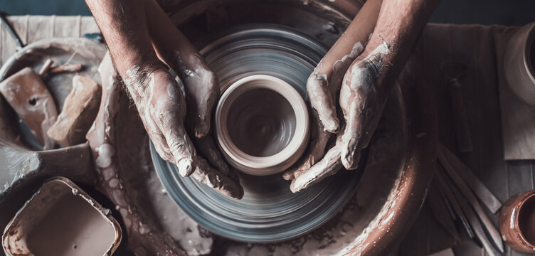 Top view of potter teaching child to make ceramic pot on the pottery wheel