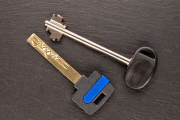 Two metal keys from a door lock on slate stone, macro, top view.
