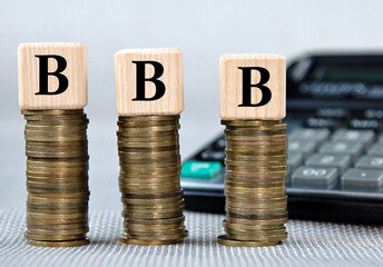 BBB - acronym on wooden cubes on the background of coins and calculator