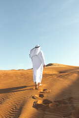 Arabian sheikh in long white dress closeup in the middle of Dubai desert.
