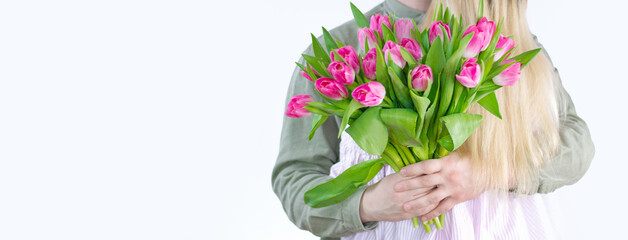 Young couple hugging with bouquet of tulips in hand isolated on white background. Space for text