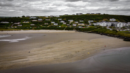 The famous Irish beach of Inchydoney at low tide, top view. Houses on the seashore. Huge sandy beach. Overcast gray sky. A small coastal settlement.