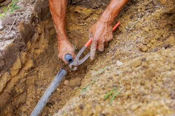 Installing an underground sprinkler system for watering yard garden man works with pipes in ground...