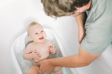 Cute newborn baby girl having fun while taking a bath. Father daughter time. - 580106340