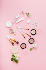 Face care and make up products with spring apple bloom (tonic or lotion, serum, cream, micellar water, cotton pads and makeup brushes) on pink background. Freshness and face care. Decorative cosmetics - 580108957
