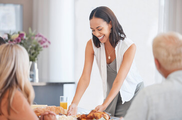 Happy woman hosting food at dinner table in home, house and dining room for family lunch, meal and social gathering together. Party, celebration and eating in family home, lifestyle and happiness