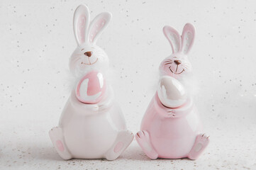 Happy Easter greeting card. Two porcelain bunnies with Easter eggs close-up and empty space for text