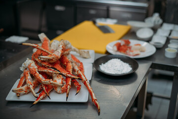 Fresh red Kamchatka crab legs on the table and ingredients in the restaurant kitchen.