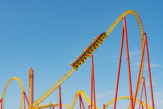 Yellow and red roller coaster with upturning trolleys on a turn and a loop.