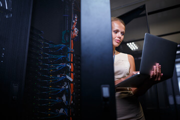 IT engineer standing amid working server racks doing routine maintenance check and diagnostics...