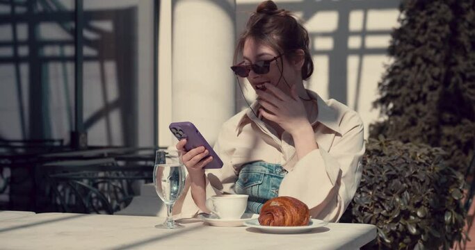 Adult girl in a summer cafe chatting on cell phone
