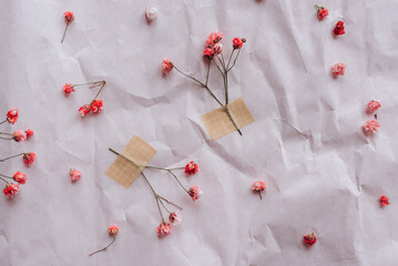 Dried pink flowers on crumpled background, top view.