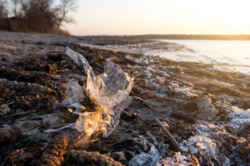 garbage plastic bags on the river bank on the beach.
