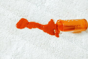 Spilling red juice a glass on a white carpet indoors. closeup. daily life stain concept