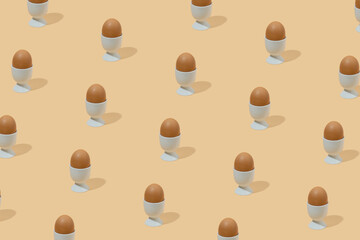 Easter pattern of brown eggs in eggcups on pastel yellow background