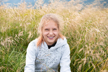 A young girl enjoys freedom, fresh air in the mountains, a young girl among tall dry grass rests and smiles, rest in mountains