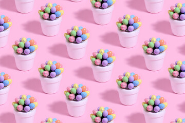 Decorative Easter eggs made of styrofoam of various colors in a white flower pot on a pink background. Easter concept.