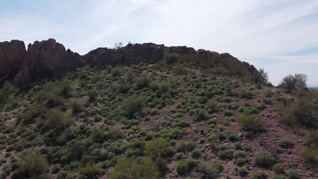 Aerial pan across a desert hillside with rugged rock outcropping