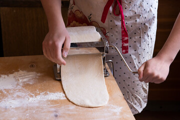 The girl rolls out the dough using a Pasta dough rolling machine.Automation of the process of working with the test at home.Spholyatella at home.the concept of technology in the confectionery Business