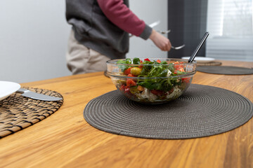 Woman with daughter setting the table for lunch time in her domestic dining room.