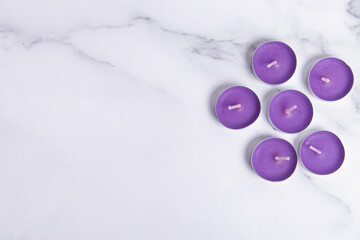 Purple scented small tea candles on marble background. Space for text. Candles for spa, holidays or home - obrazy, fototapety, plakaty