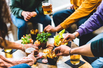 Group of happy friends eating food and drinking beer  at brewery pub restaurant- Young people enjoying happy hour with appetizer gourmet at bar table- Life Style Dining and   Beverage concept