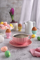 Happy Easter and spring holiday concept. Pink coffee couple with espresso surrounded by colorful Easter eggs on a light gray background. Concept for wishing a good Easter morning.