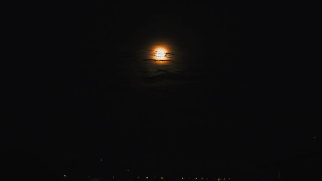 The Moon is the only natural satellite of the Earth. An accelerated video of the moonrise from behind Lake Onega. Evening turns into night. Disk full moon. The moon path is reflected in the water