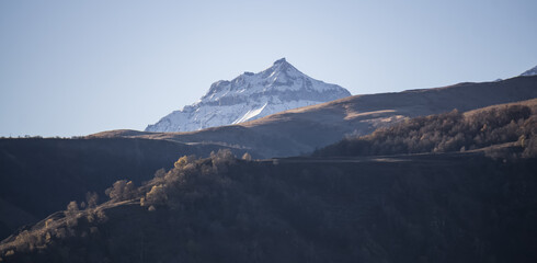 Panorama of mountain slopes with vegetation and trees yellowed in autumn and a rocky massif with...