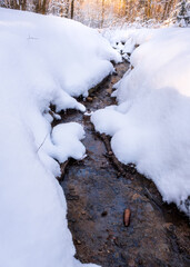 Tiny stream of water surrounded by fresh snow in local park at gothenburg sweden